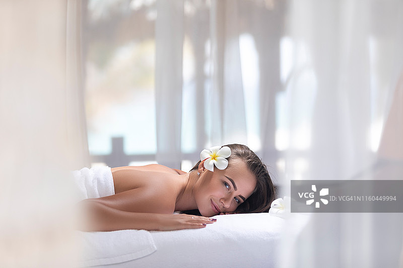 年轻女人在海滩凉亭的按摩床上图片素材