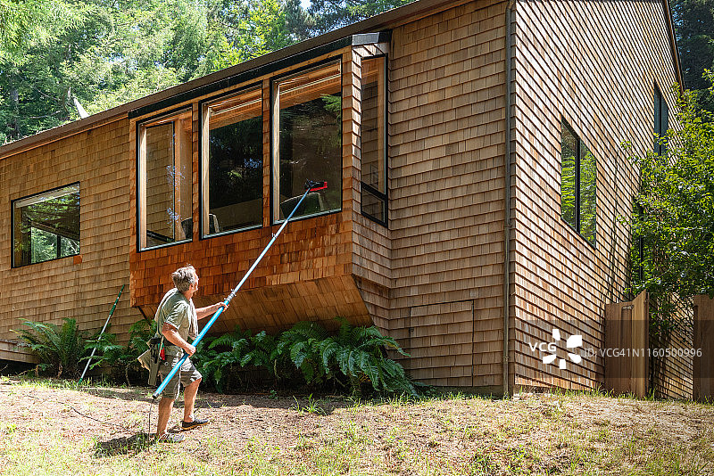 男人用长杆刷子擦窗户图片素材