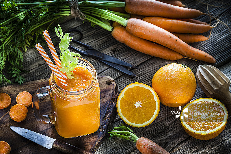 健康饮品：乡村木桌上的橙子和胡萝卜汁图片素材