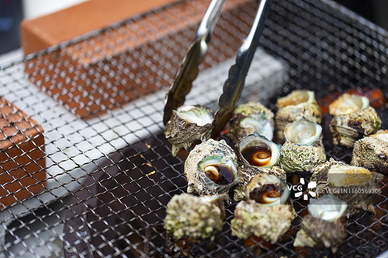 热炭炉上烤制的蝾螺，日式新鲜海鲜烧烤图片素材
