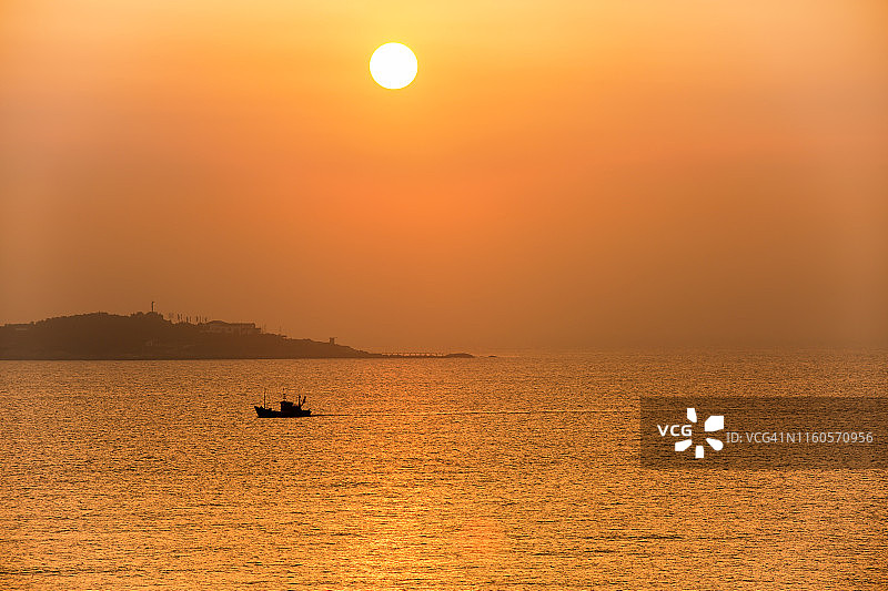 中国山东省胶州湾海上日出与渔船图片素材
