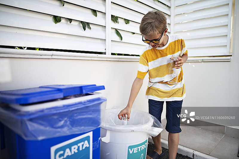 小男孩将玻璃瓶扔进分类垃圾箱图片素材