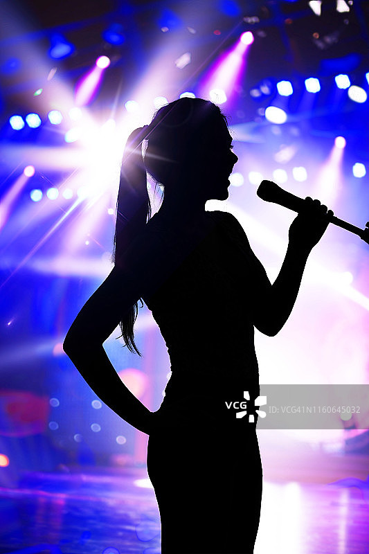 在演唱会舞台上唱歌的女性轮廓图片素材