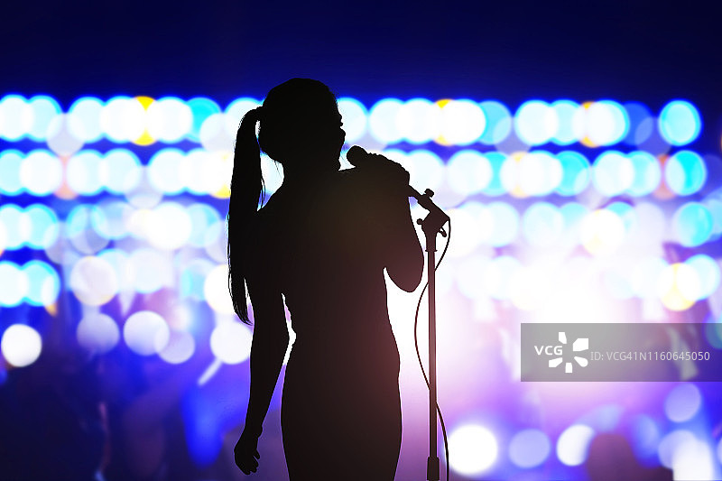 演唱会舞台剪影：在人群面前唱歌的女人图片素材