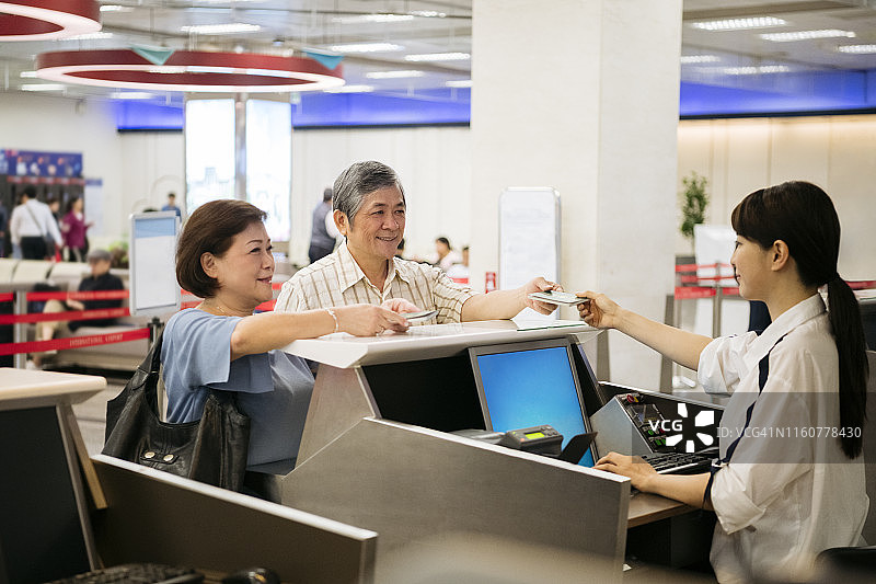 情侣在机场办理登机手续时出示护照图片素材