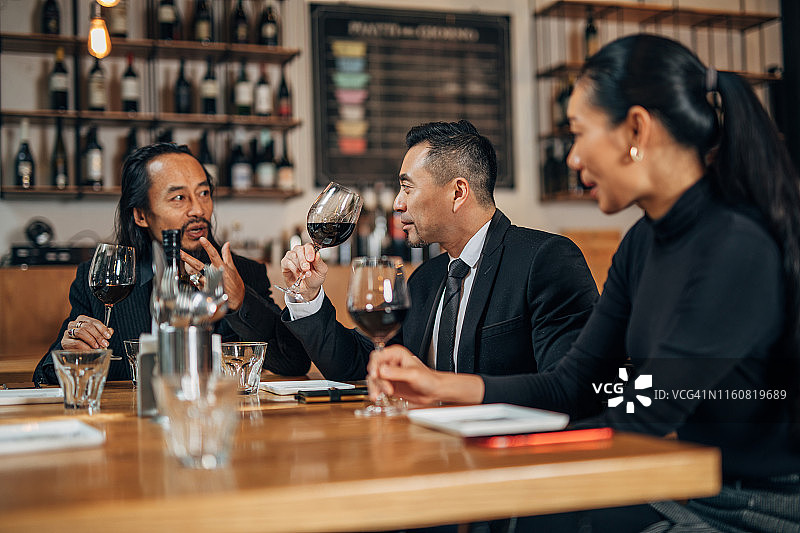 商务人士坐在餐厅里喝葡萄酒图片素材