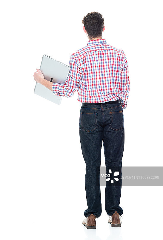 穿着格子衬衫和牛仔裤，使用笔记本电脑的迷人年轻人图片素材