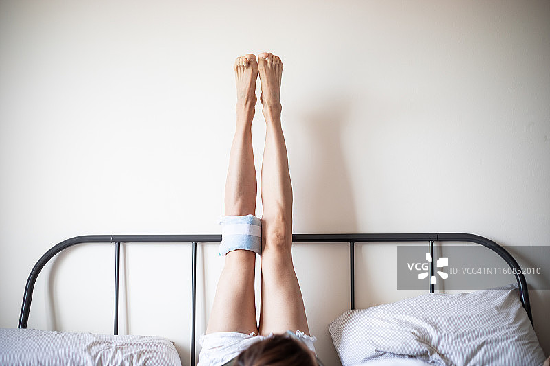 抬起双腿并在一个膝盖上敷冰袋的女人图片素材