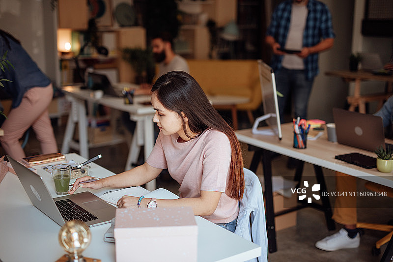 在繁忙的现代工作场所中的年轻亚洲女士肖像图片素材