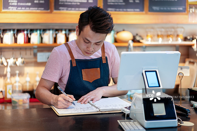 服务员在咖啡馆的柜台上对着电脑做笔记图片素材