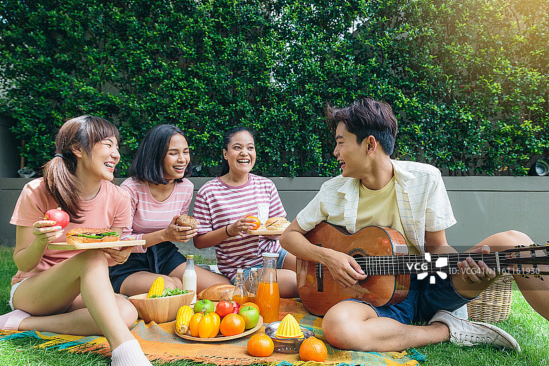 一群快乐的亚洲朋友在户外公园野餐，健康食品和生活方式概念图片素材