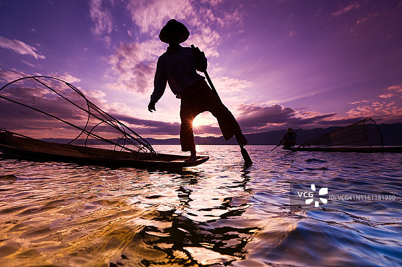 缅甸茵莱湖日落时分用腿划船的渔民图片素材