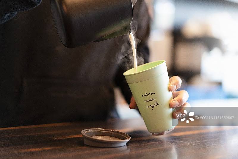 男子将热牛奶倒入外带咖啡杯中，特写图片素材