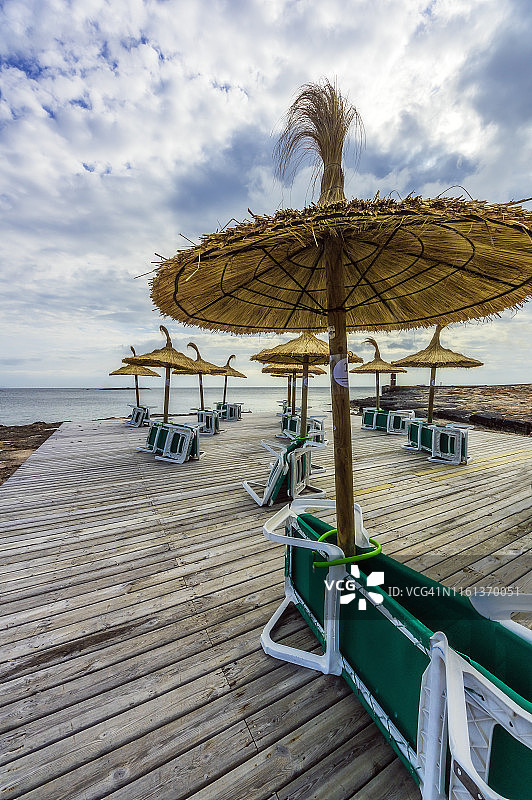 马略卡岛圣乔治殖民地的木制露台与茅草伞和日光躺椅图片素材