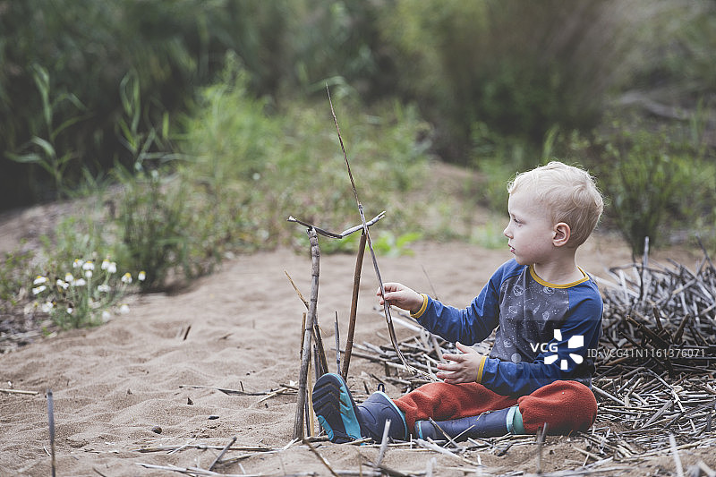 在沙滩上玩树枝的男孩图片素材