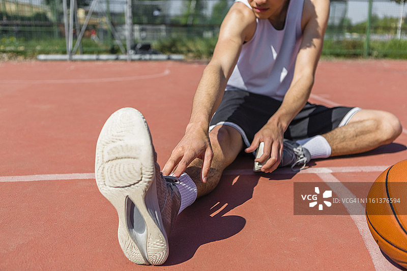 年轻的篮球运动员伸展腿部图片素材