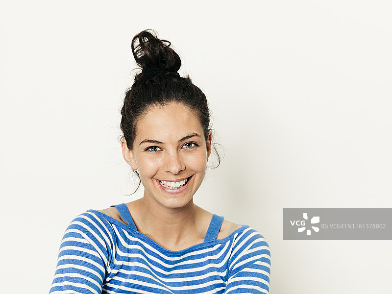 在白色背景前摆姿势的黑发蓝白条纹毛衣年轻女子图片素材