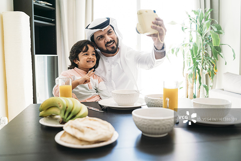 阿拉伯男子和儿子在早餐时自拍图片素材