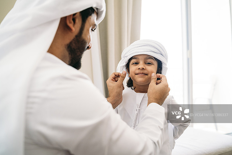 阿拉伯男人为儿子整理头巾图片素材