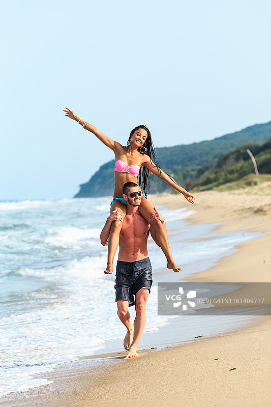 在海滩上玩背背的快乐年轻情侣图片素材