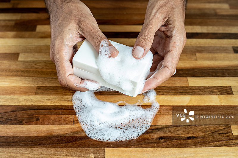 男性手持白色有机肥皂/洗发水特写图片素材