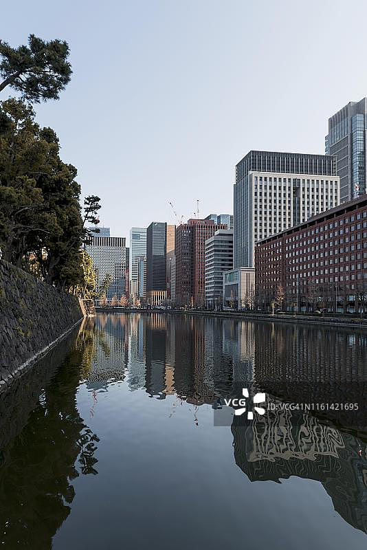 东京千代田区皇居外苑的运河中倒映着高层建筑图片素材