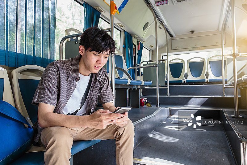 年轻的亚洲游客在巴士上用手机旅行图片素材