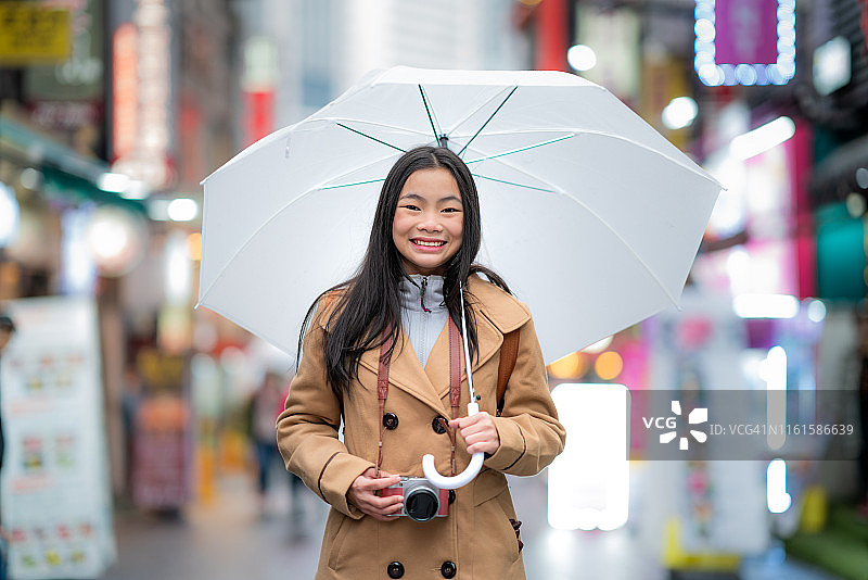 旅行者亚洲女人在韩国首尔明洞购物街下雨时拿着雨伞图片素材