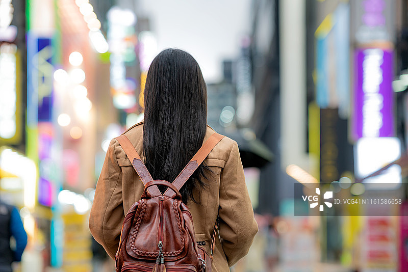 亚洲女性在韩国首尔明洞购物街的灯光下行走。图片素材