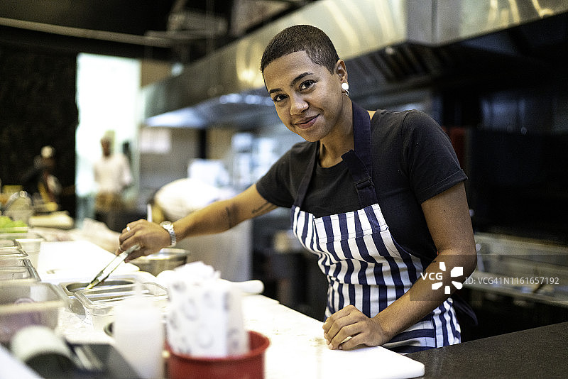 在商业厨房准备饭菜的女厨师肖像图片素材