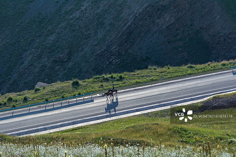 在高速公路上骑马的哈萨克牧民图片素材