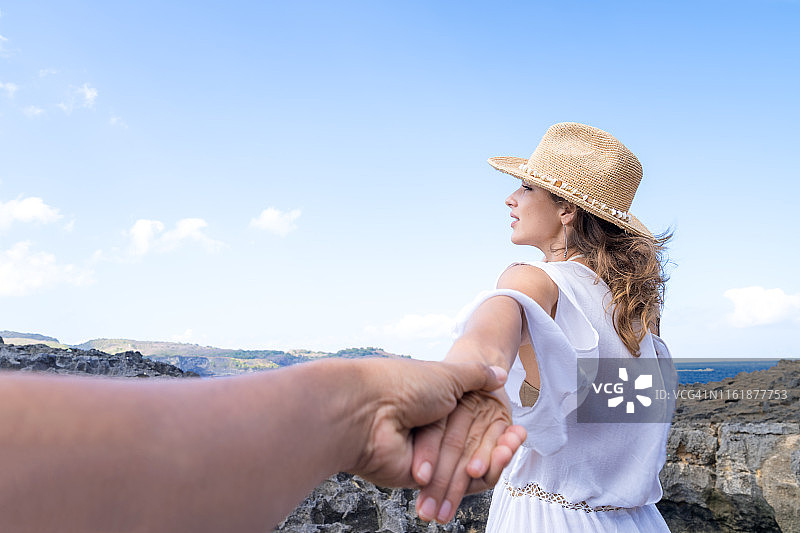 在印度尼西亚巴厘岛努沙佩尼达岛，身穿白色连衣裙的女游客抱着她的丈夫。图片素材