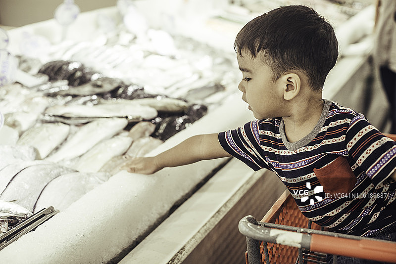 幼儿男孩在商店里玩螃蟹图片素材