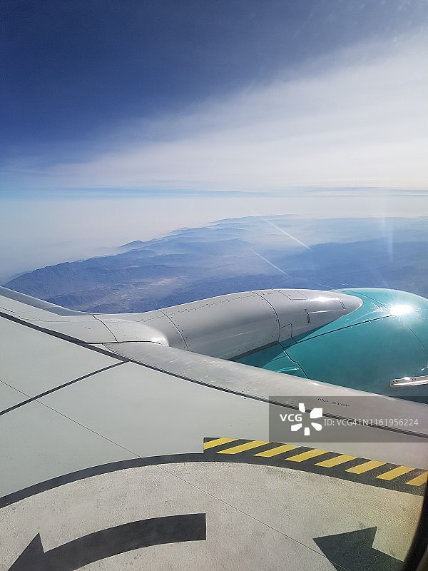飞机舷窗视角：飞越荒漠，机翼掠过云层图片素材