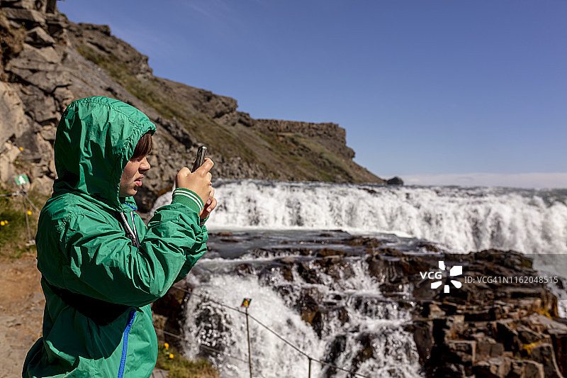 年轻可爱的男孩在黄金瀑布拍照图片素材