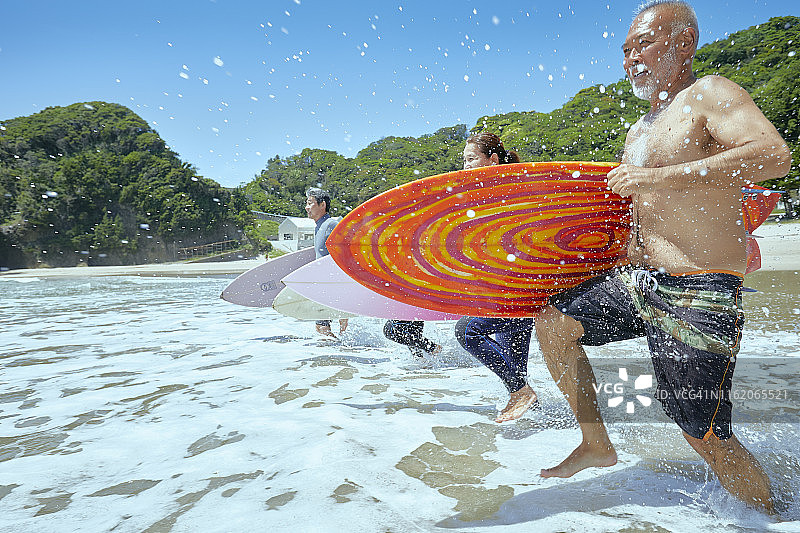 带着冲浪板冲向海浪的年长冲浪者图片素材