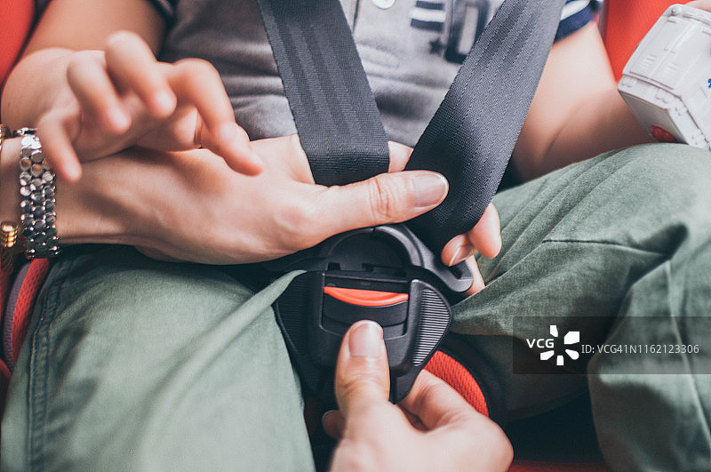 年轻母亲将儿子固定在婴儿汽车座椅上图片素材