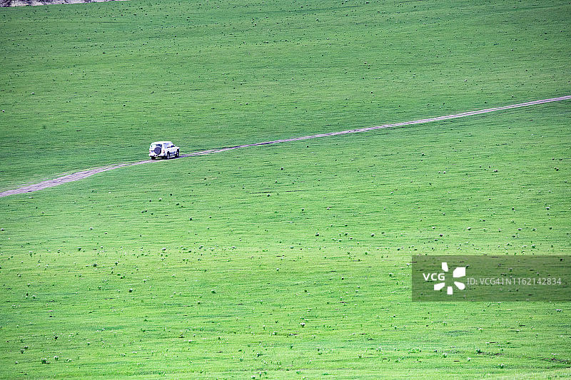 SUV在空旷的草原景观中行驶图片素材