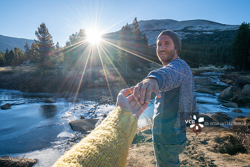 “跟我来”概念：年轻男子带领女友在日出时前往河边图片素材