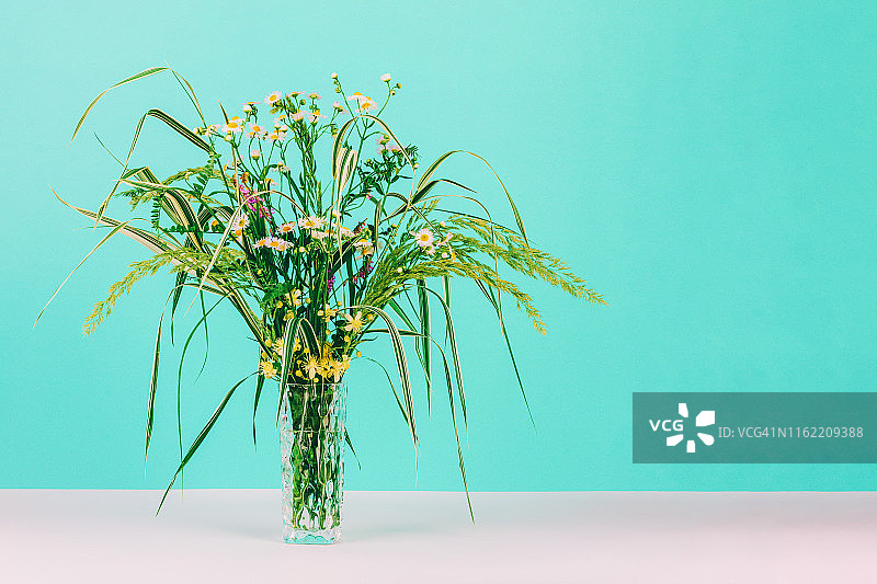 夏季绿色草本和洋甘菊玻璃花瓶花束薄荷色背景图片素材