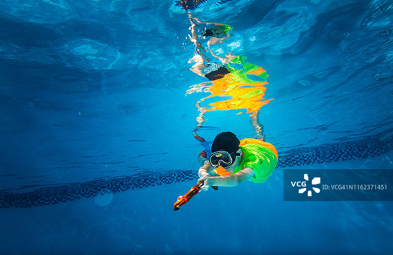 在游泳池里带着浮潜装备和鱼叉的孩子图片素材