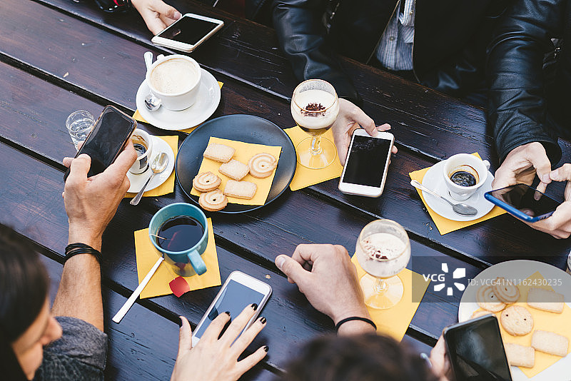 朋友们在户外早餐时使用移动设备图片素材