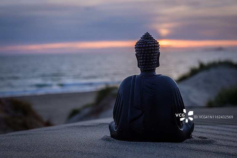 沙滩上的坐佛，背景是沙丘和海洋日落美景图片素材
