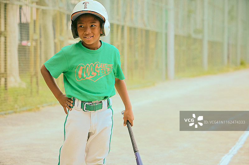 儿童（6-7岁）在球场上拿着棒球棒微笑图片素材