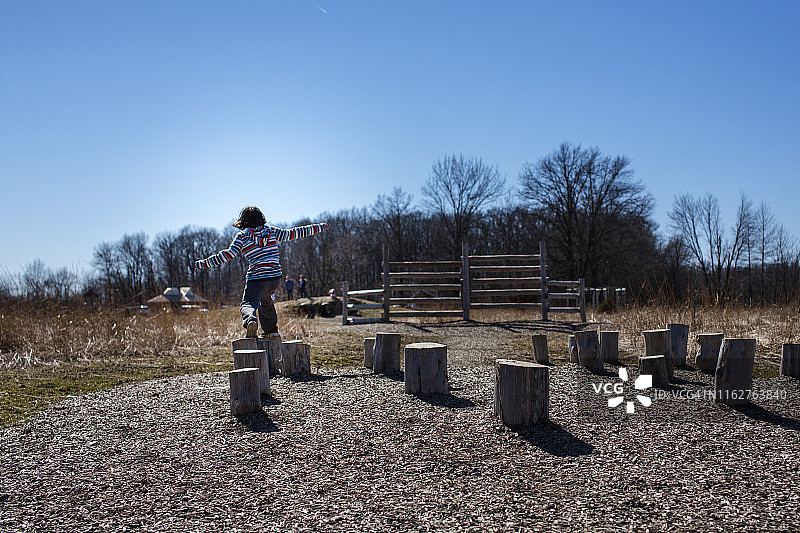 孩子在户外障碍赛中跳过树桩图片素材