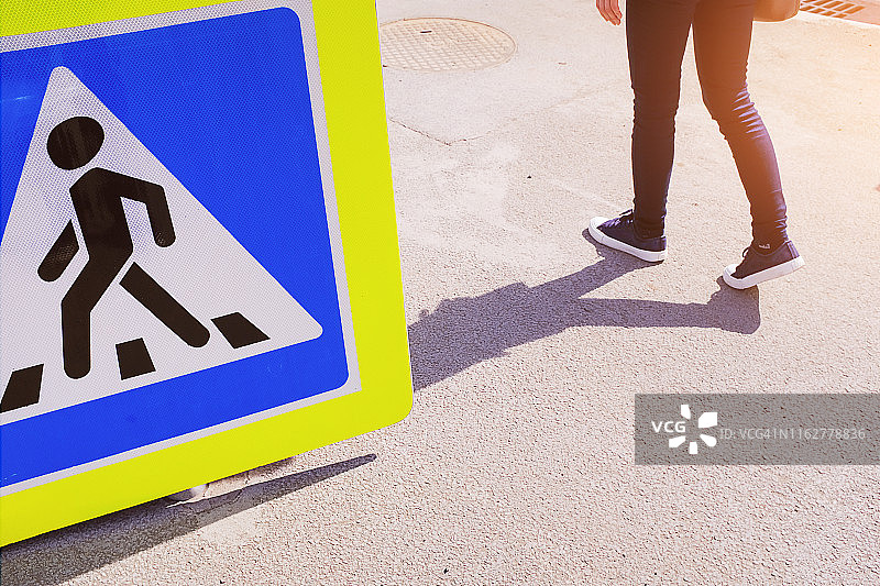人行横道标志未安装在沥青路面上，旁边站着一个女孩图片素材