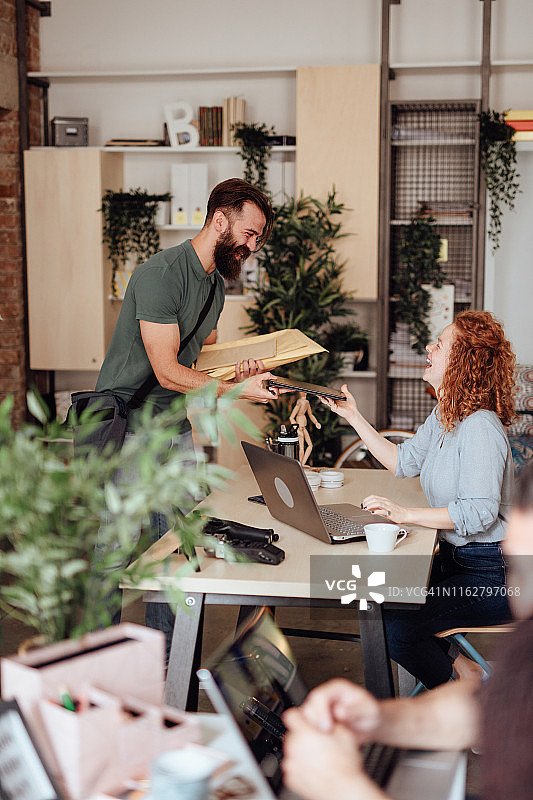 男快递员在现代办公室送包裹图片素材