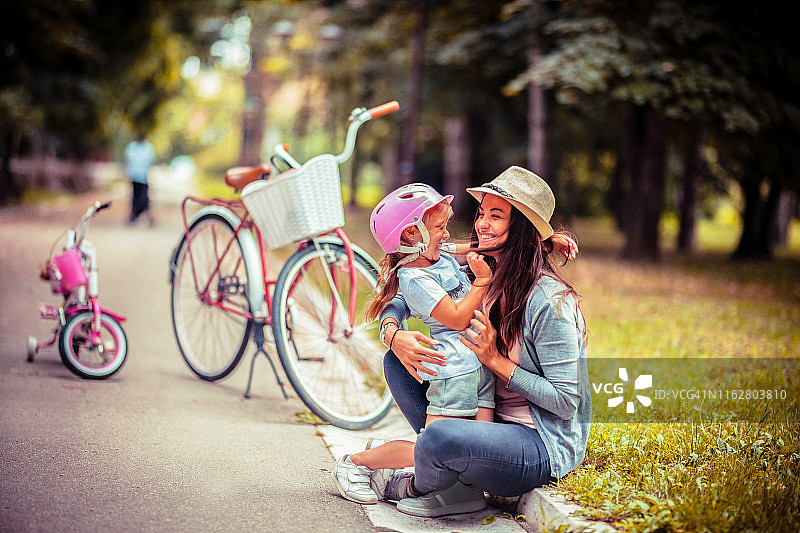 母亲在公园里骑自行车带着孩子图片素材
