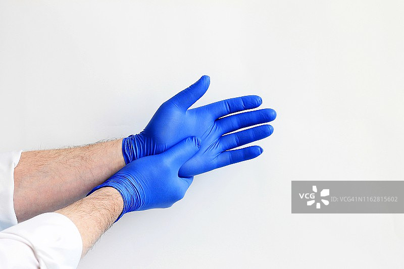 医药外科主题：医生戴上蓝色防护手套。图片素材