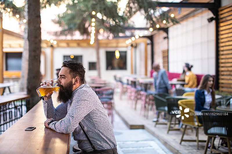 男人独自在户外酒吧喝啤酒图片素材